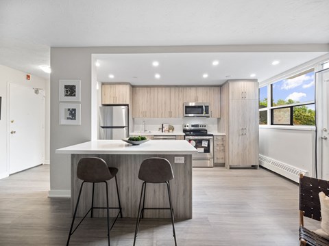 A modern kitchen with a bar area and two chairs.