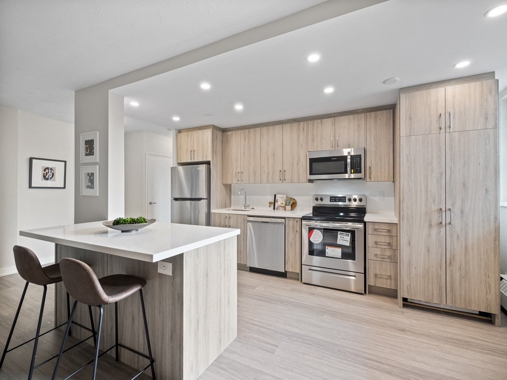 a kitchen with wooden cabinets and a white island with two stools