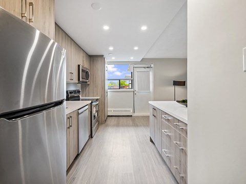 A modern kitchen with a refrigerator on the left and a counter on the right.
