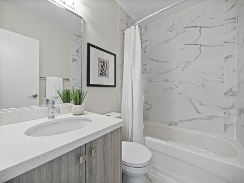 A bathroom with a marble wall and a white tub.