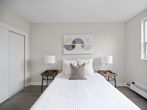 A bedroom with a large bed, two lamps, and a painting on the wall.
