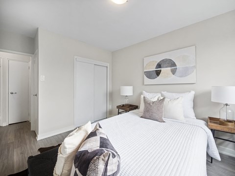 A bedroom with a large bed and a painting on the wall.