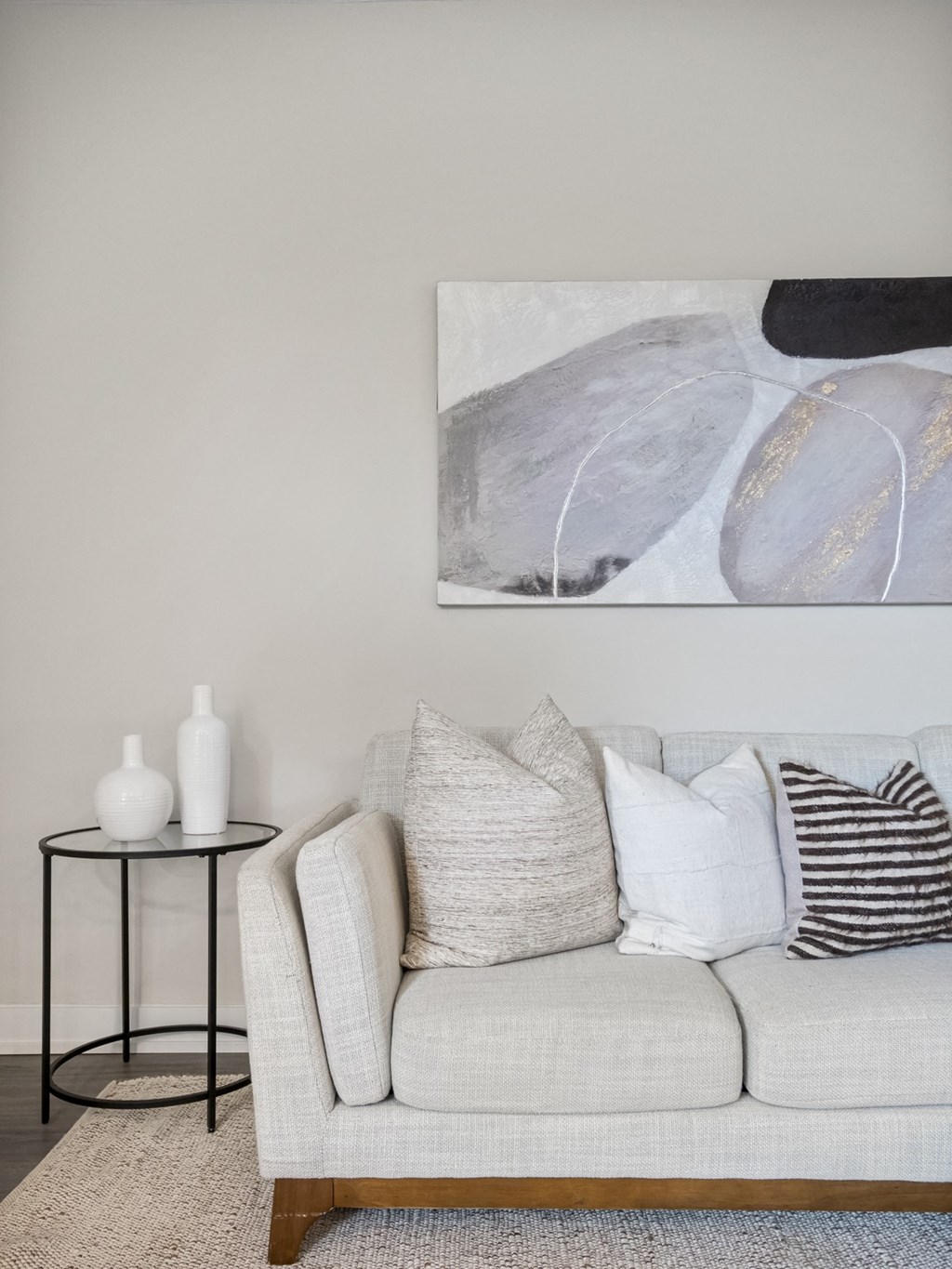 a living room with a white couch and a large painting on the wall