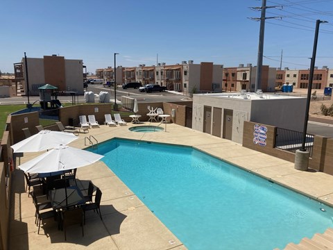 a swimming pool on the roof of a building with chairs and umbrellas