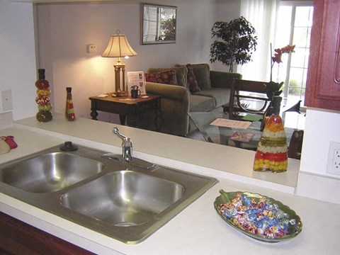 A kitchen with a silver sink and a decorative plate of candy.