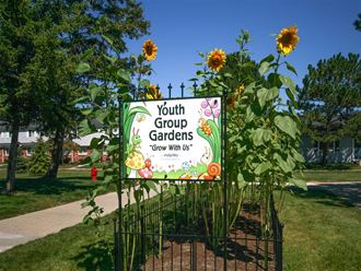 a sign for youth group gardens in a garden with sunflowers