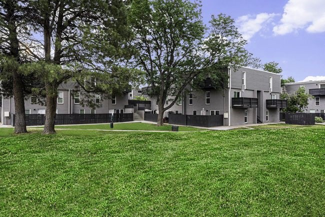 A grassy area in front of a building with trees.