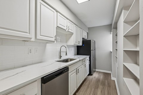A kitchen with white cabinets and a black refrigerator.