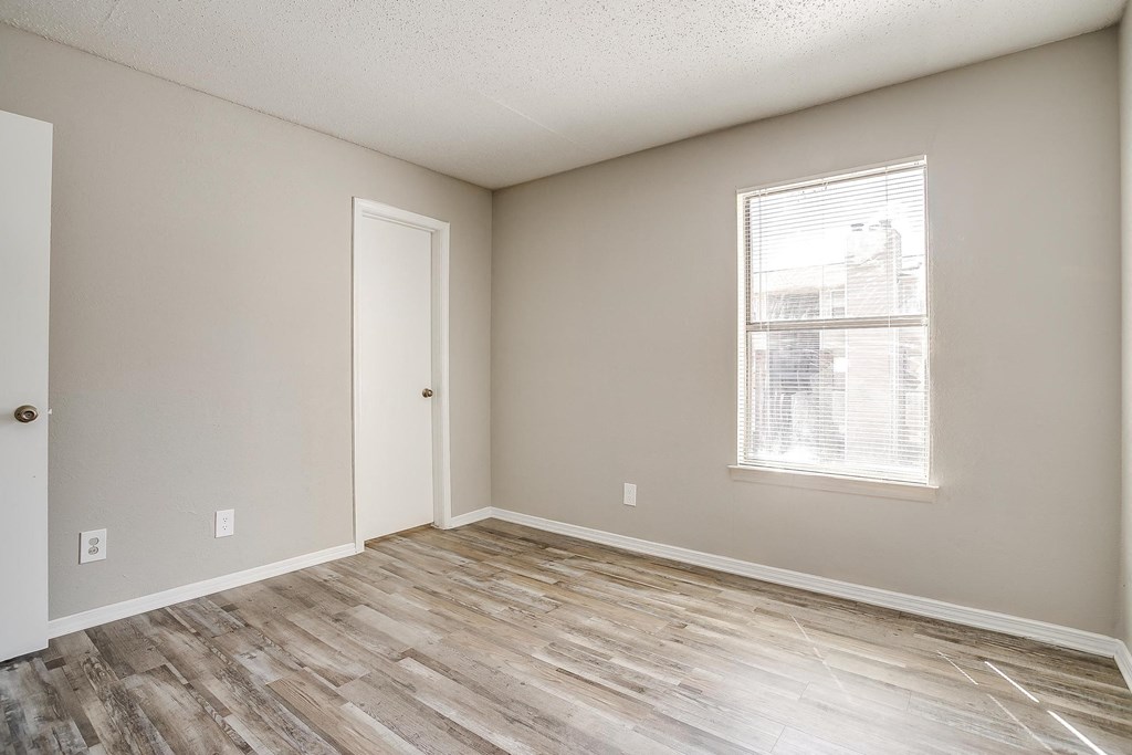 an empty living room with wood flooring and a window