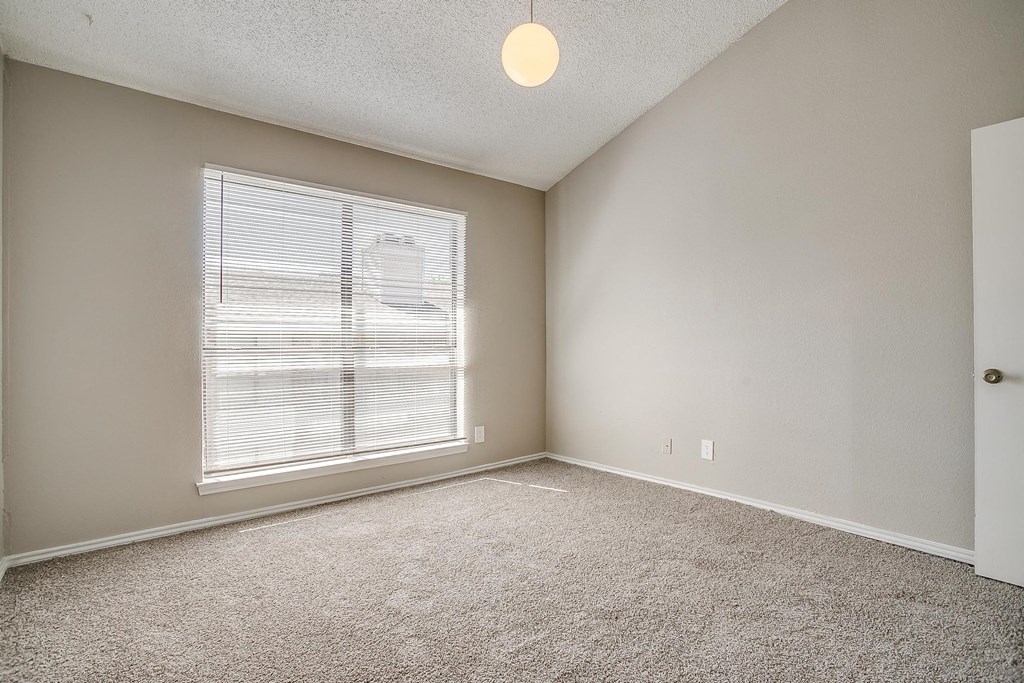 an empty living room with a large window and carpet