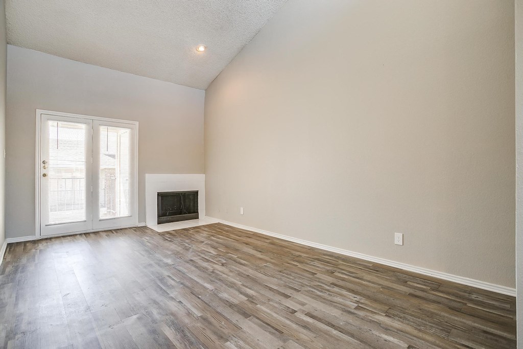 an empty living room with wood floors and a fireplace