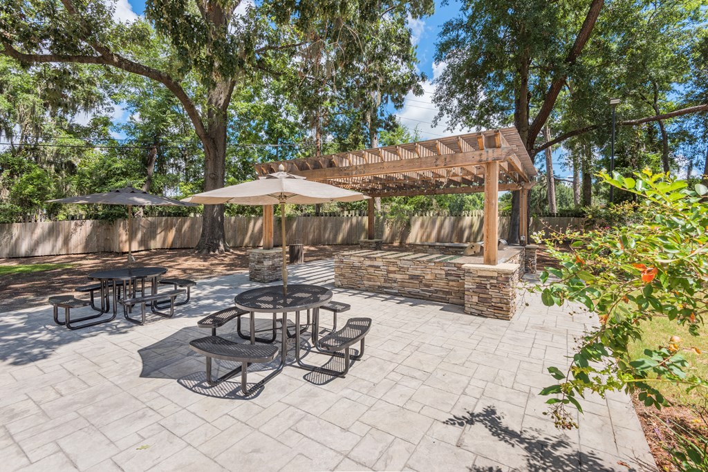 a patio with a pergola and tables with umbrellas