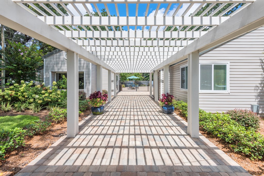 a pergola with a brick pathway in front of a house