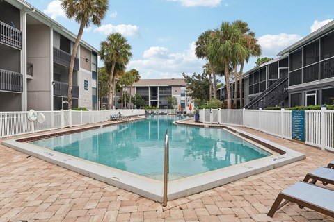A rectangular pool with a white border and a white fence around it.