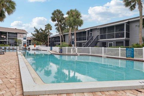A swimming pool surrounded by palm trees and a building.