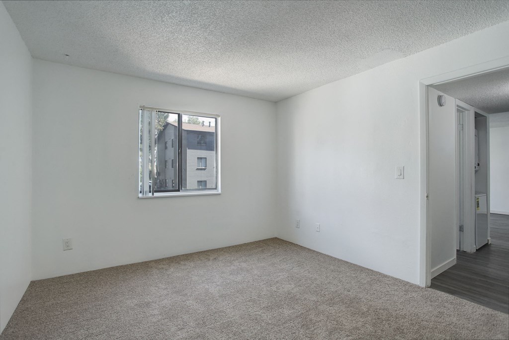 an empty living room with white walls and a window