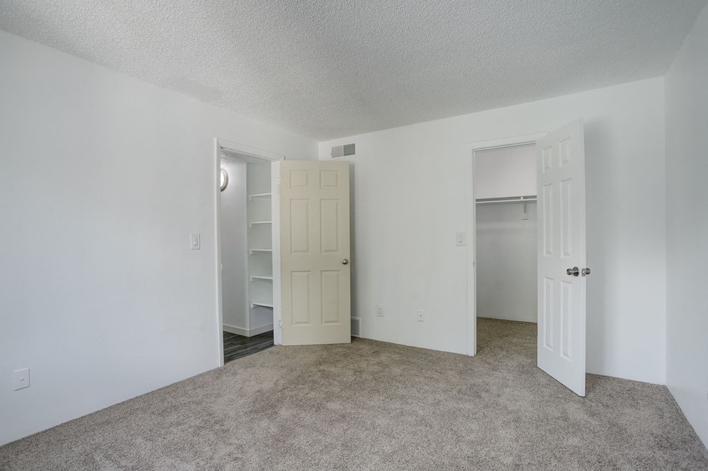 an empty bedroom with a closet and an open door