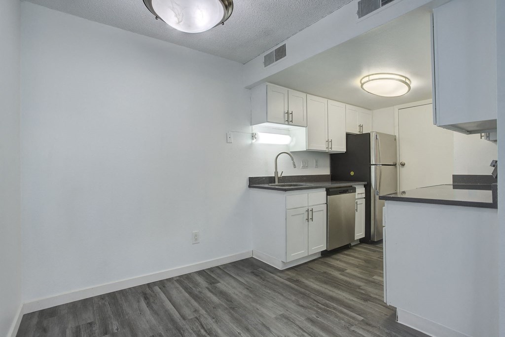 an empty kitchen with white cabinets and a stainless steel refrigerator
