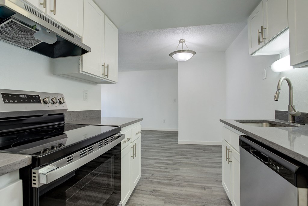 an empty kitchen with white cabinets and stainless steel appliances