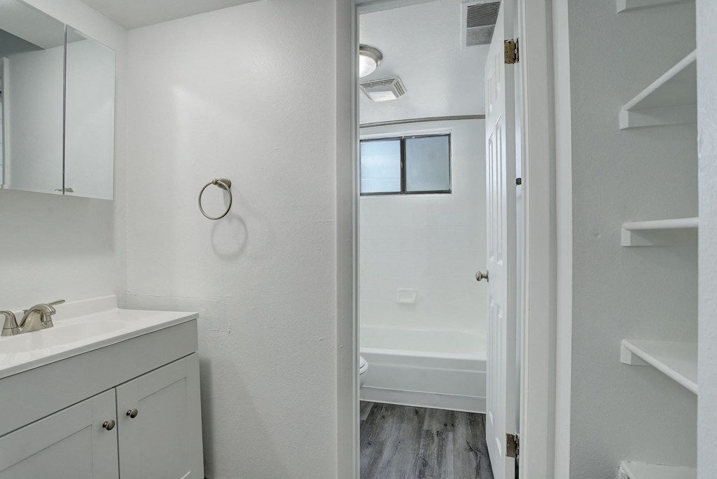 a bathroom with white cabinets and a shower and a sink