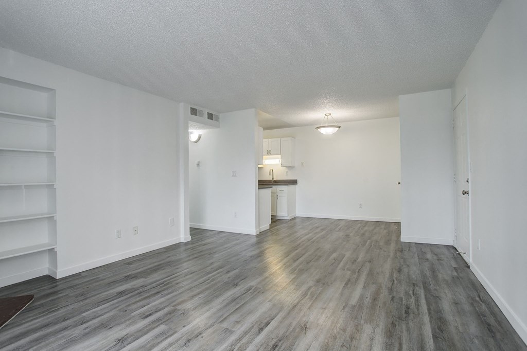 an empty living room with white walls and wood flooring