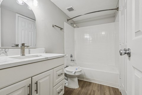 A white bathroom with a toilet, sink, and bathtub.