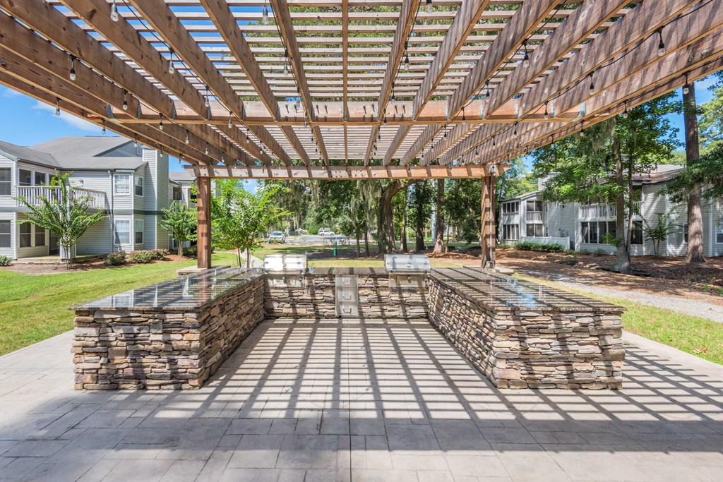 an outdoor patio with a wooden pergola and stone walls