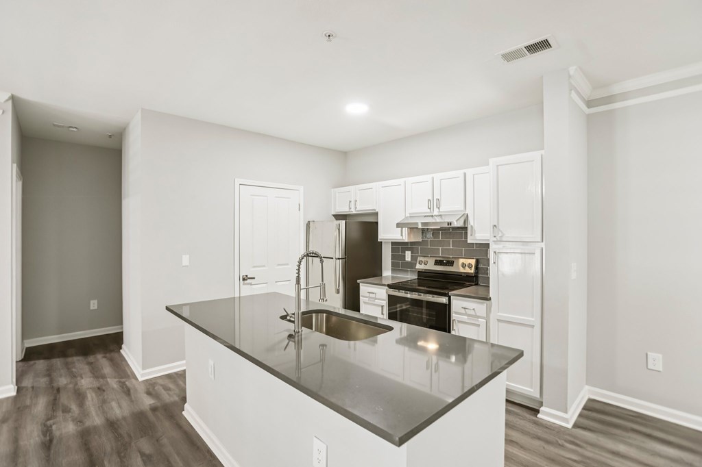 A kitchen with a black granite countertop and white cabinets.