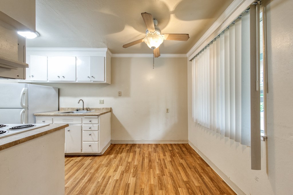 a kitchen with white cabinets and a ceiling fan