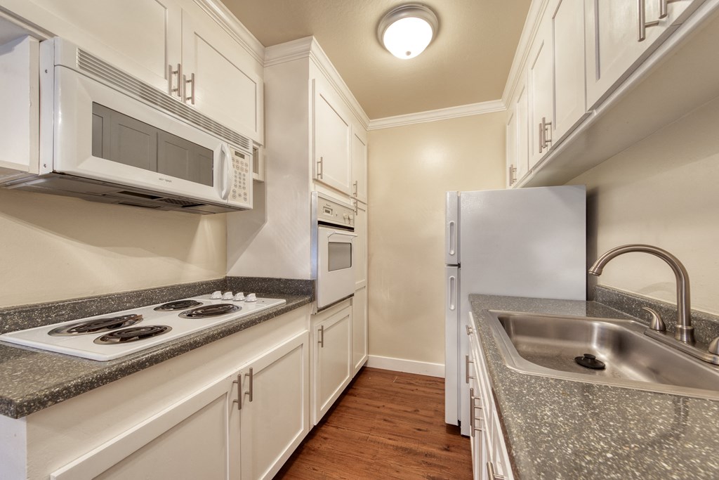a kitchen with white cabinets and gray countertops