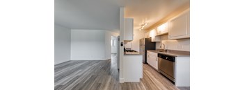 A kitchen with white cabinets and a black refrigerator.