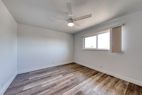 the spacious living room with wood flooring and a ceiling fan