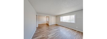 A room with wooden flooring and a window with blinds.