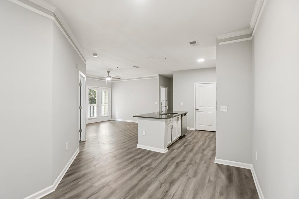 A spacious kitchen with white cabinets and a wooden floor.