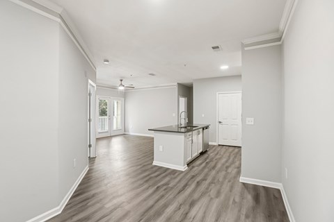 A spacious kitchen with white cabinets and a wooden floor.