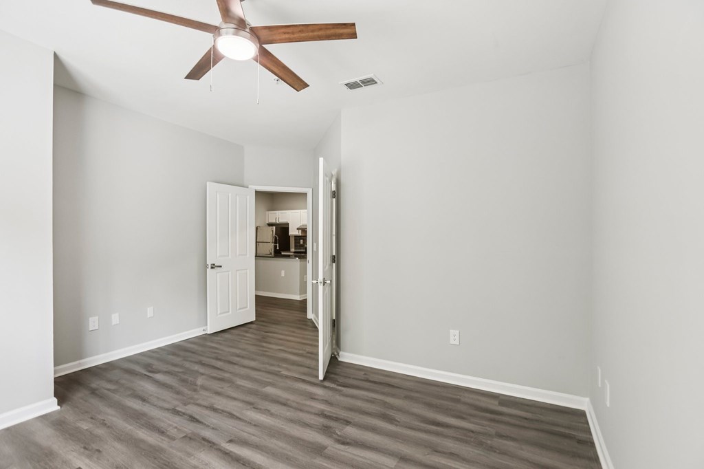 A room with a ceiling fan and a doorway leading to another room.