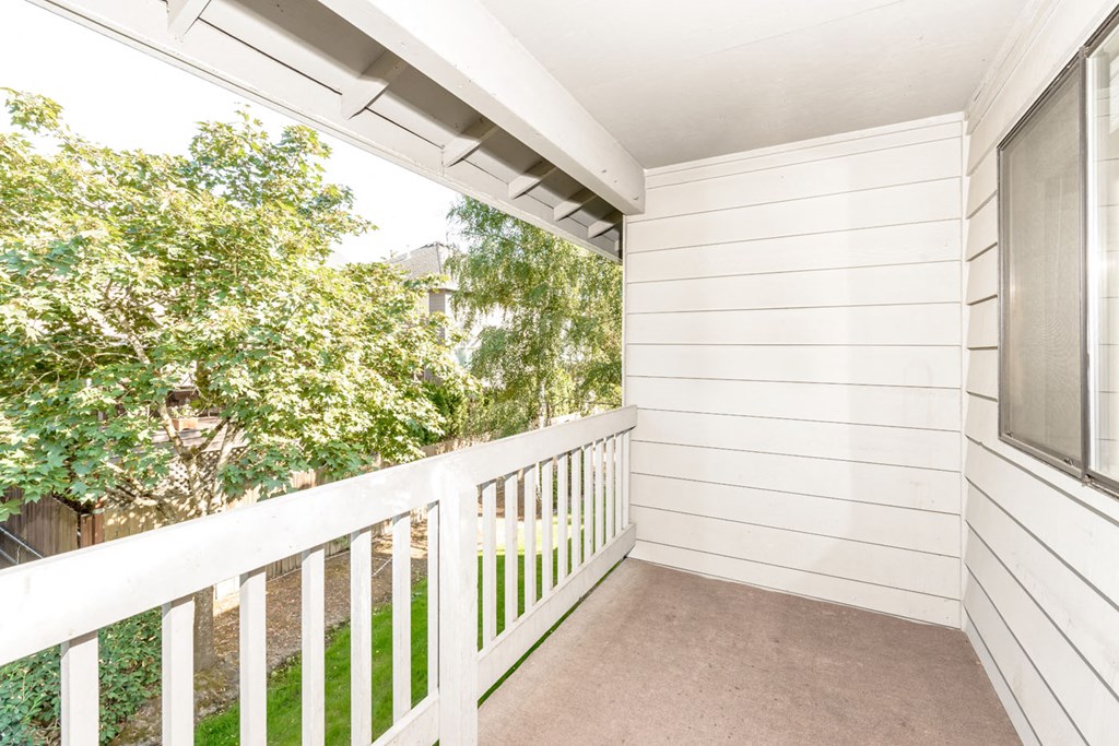 a balcony with a white railing and trees in the background