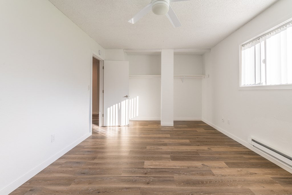 a bedroom with hardwood floors and white walls