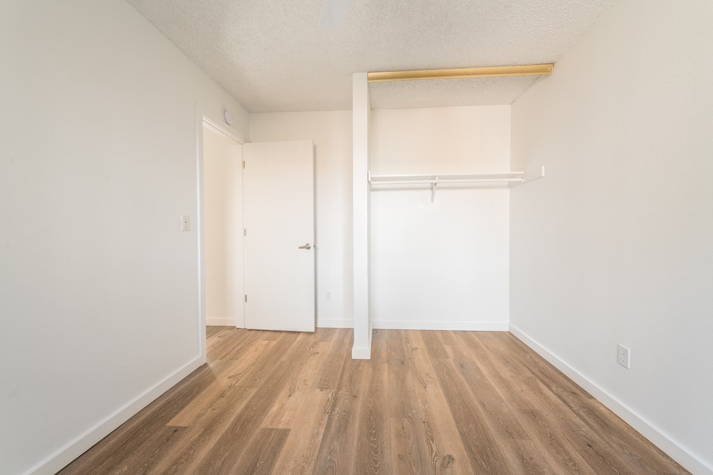 a bedroom with hardwood floors and white walls