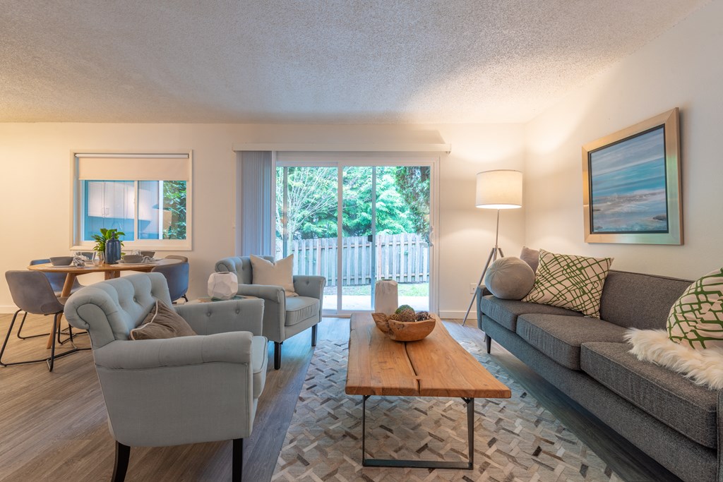 a living room with couches chairs and a coffee table in front of a sliding glass door
