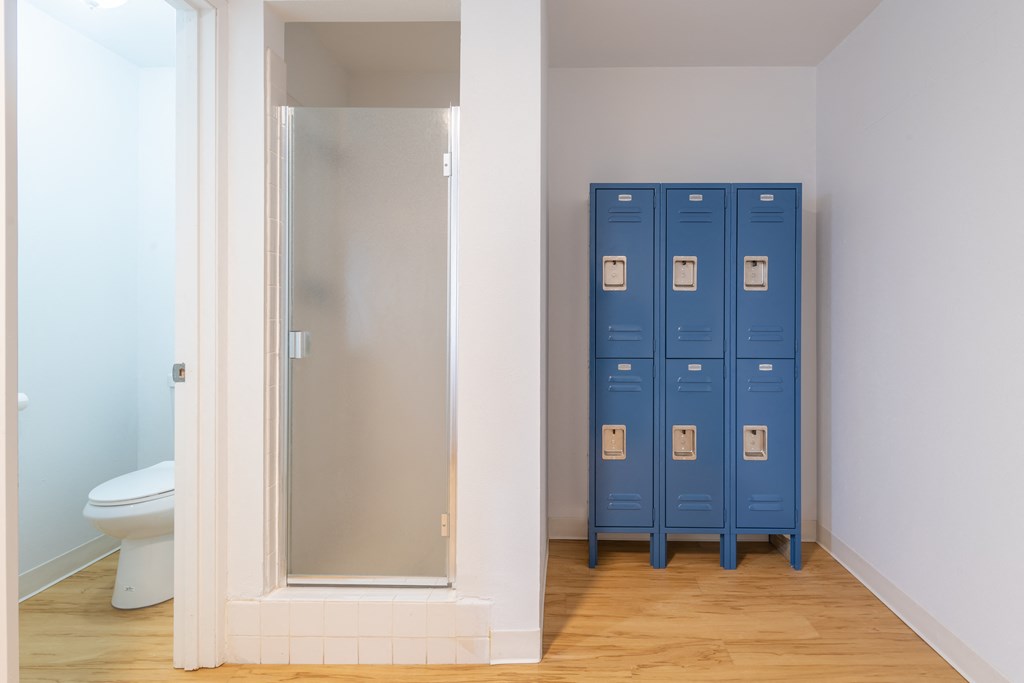 a bathroom with blue lockers and a toilet