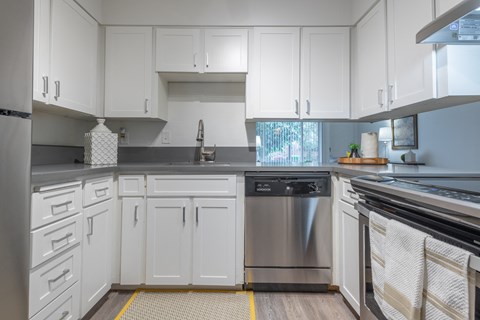 a white kitchen with stainless steel appliances and white cabinets