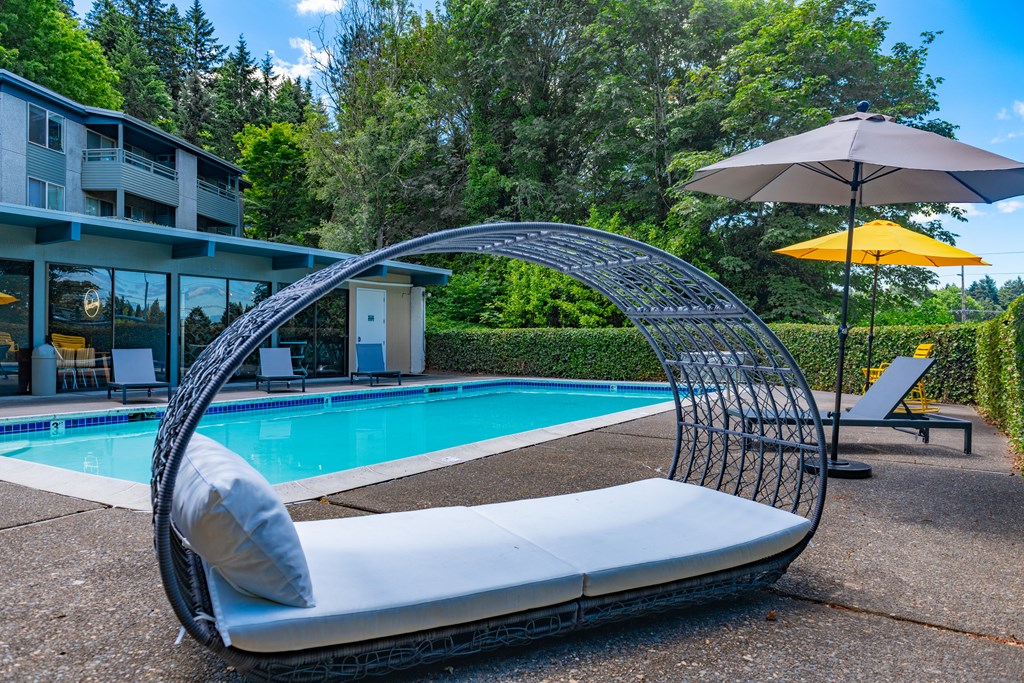 a lounge chair next to a pool in front of a building