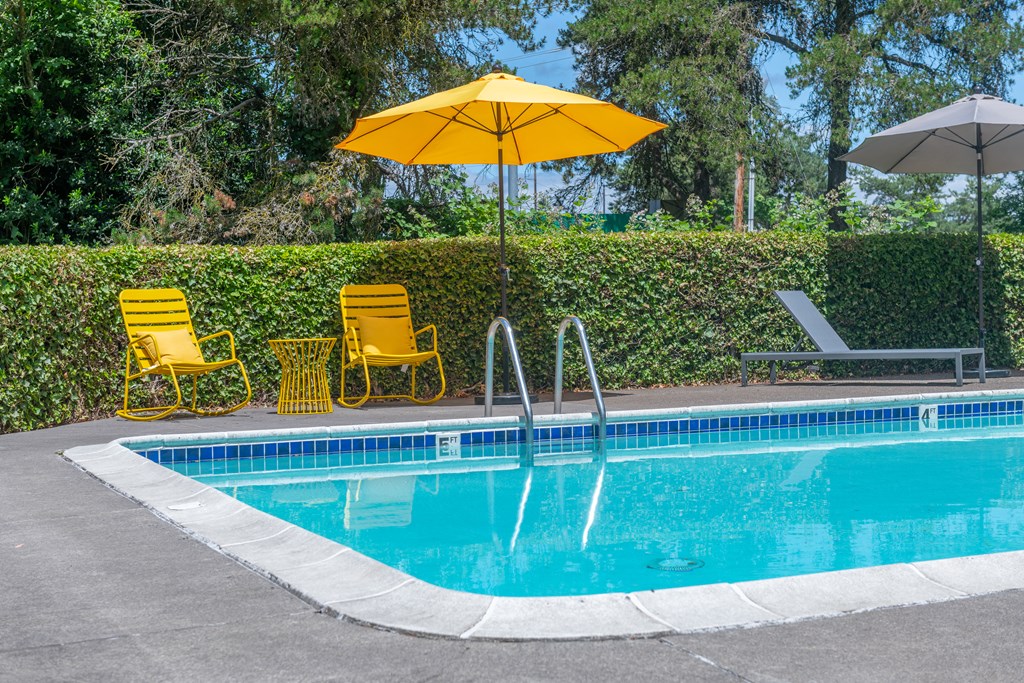 a swimming pool with yellow chairs and an umbrella