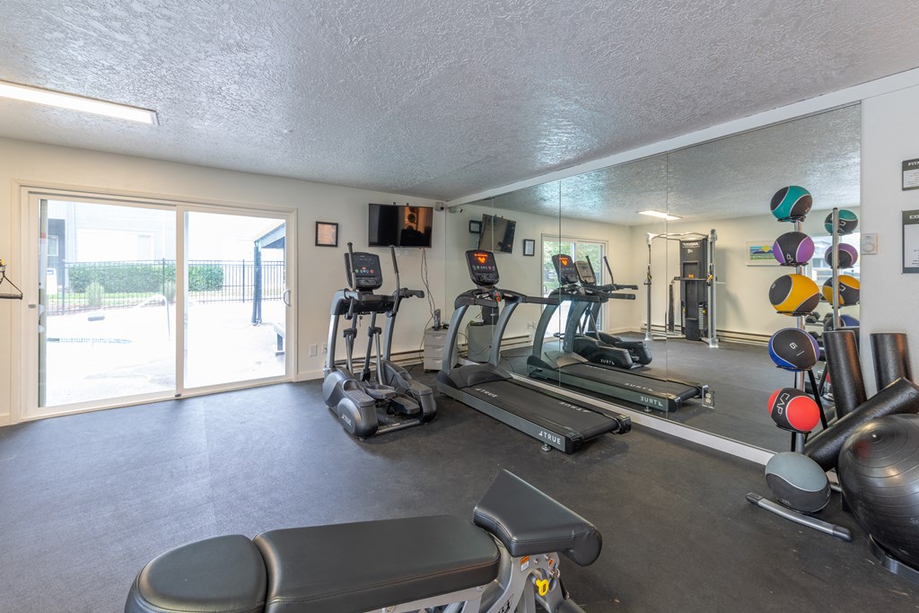 a gym with cardio equipment and a sliding glass door