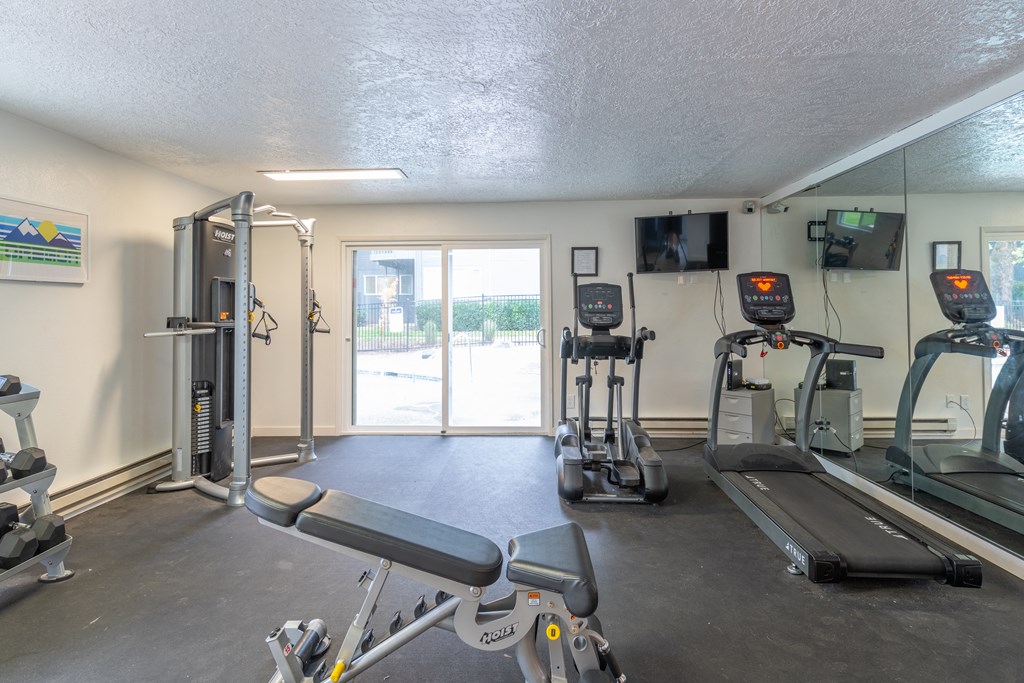 a gym with cardio equipment and a sliding glass door
