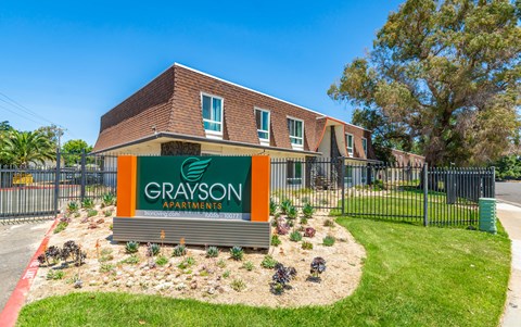 a green and orange sign in front of a brick building