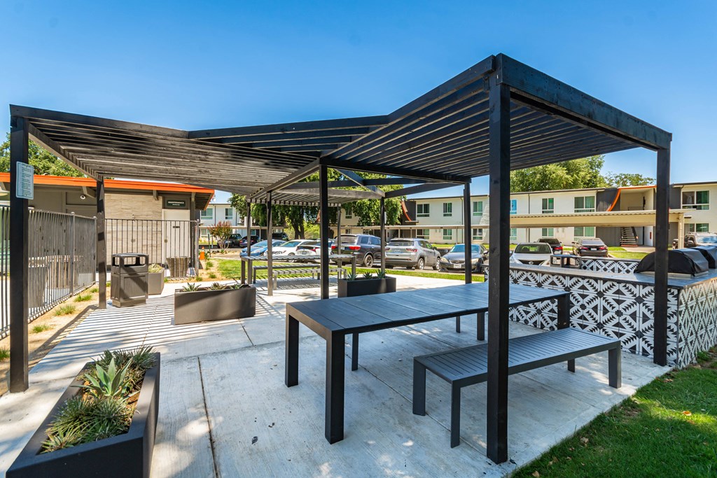 a picnic table and bench under awning on a concrete patio