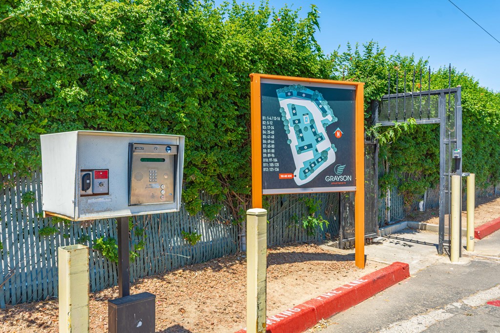 a sign with a map and a ticket machine in front of a hedge