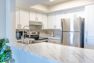 a kitchen with white cabinets and a white marble counter top